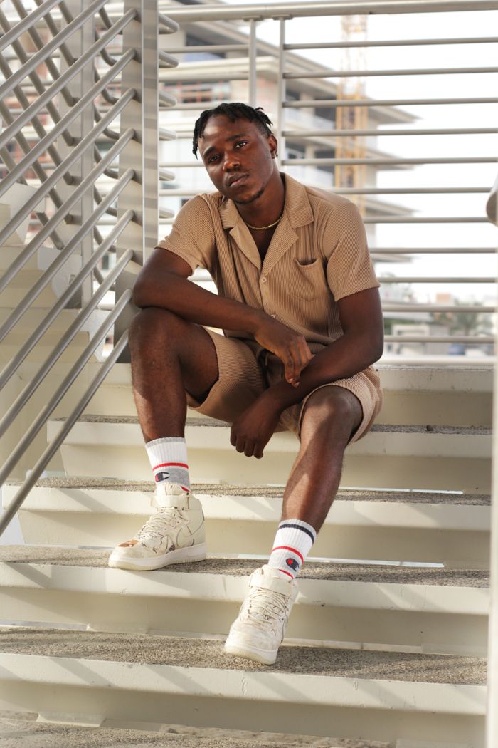 gallery-02 African American man in fashionable attire sitting on a modern outdoor staircase in Dubai.
