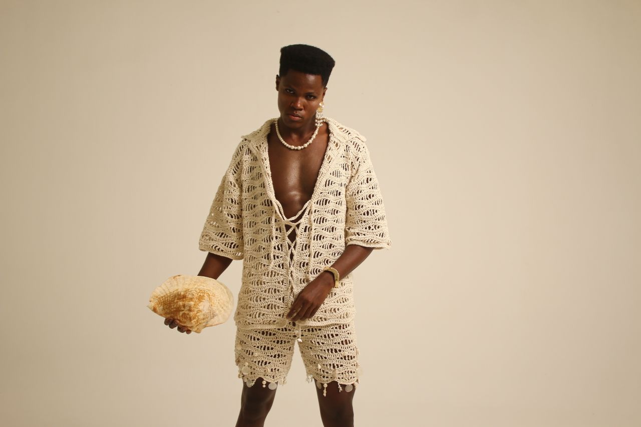 our-story Stylish young adult in crochet outfit holding a seashell in studio.