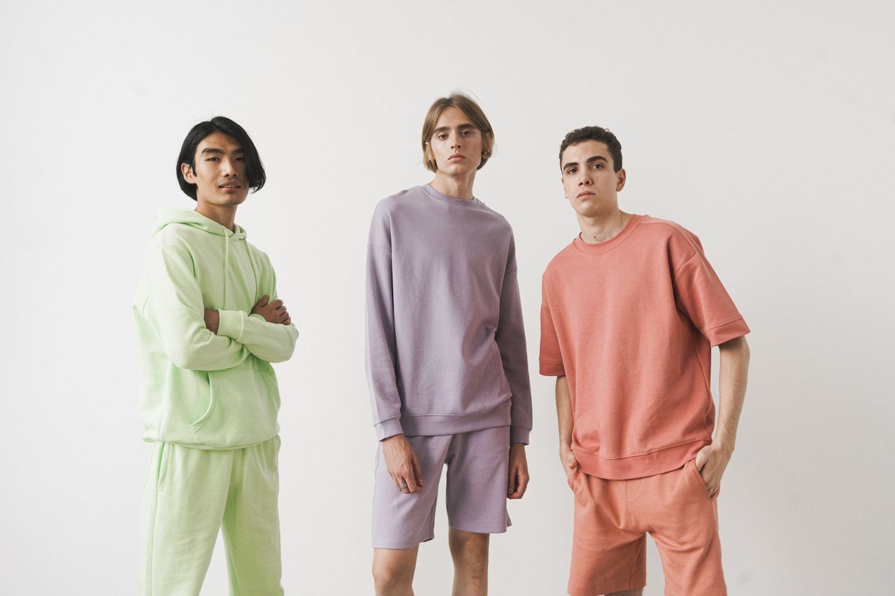 home-img Three men wearing pastel loungewear poses in a studio, showcasing modern casual fashion.